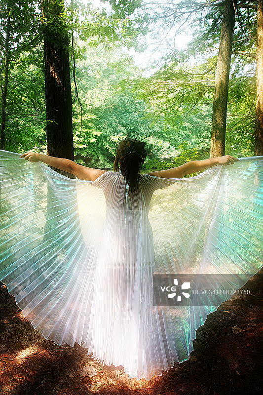 在森林里展开白色翅膀的年轻女人图片素材