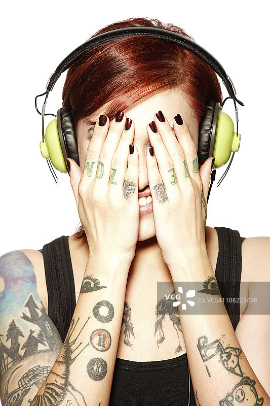 用手捂住脸听耳机的年轻女人图片素材
