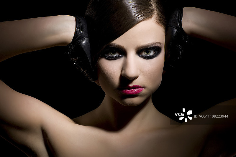 美丽的深色头发年轻女人，黑色眼妆和手套图片素材