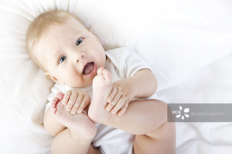 微笑的宝宝在玩自己的脚图片素材