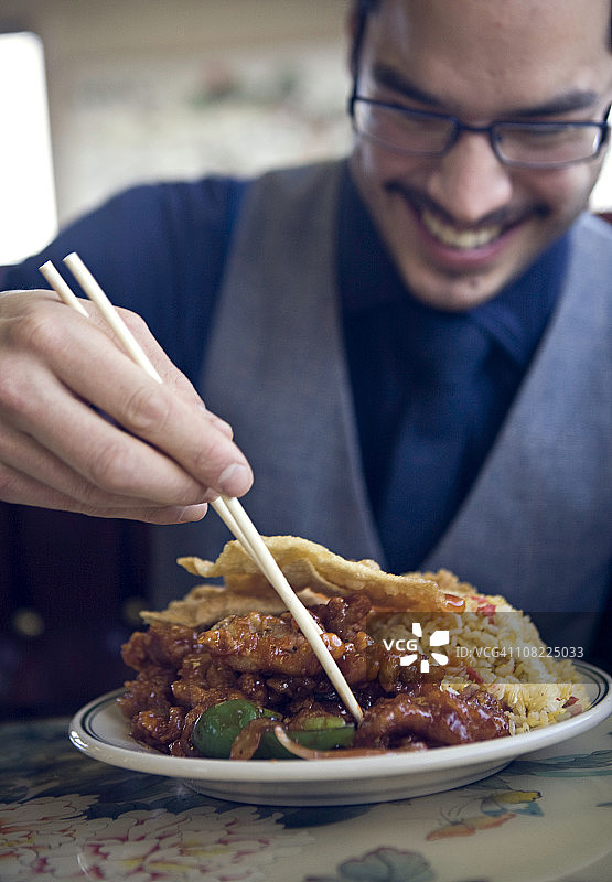 快乐的年轻男人吃中餐图片素材