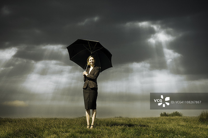 暴风雨天气下撑伞的女商人图片素材