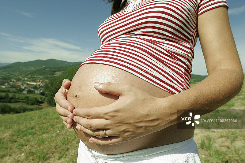 女人展示孕肚，站在户外图片素材