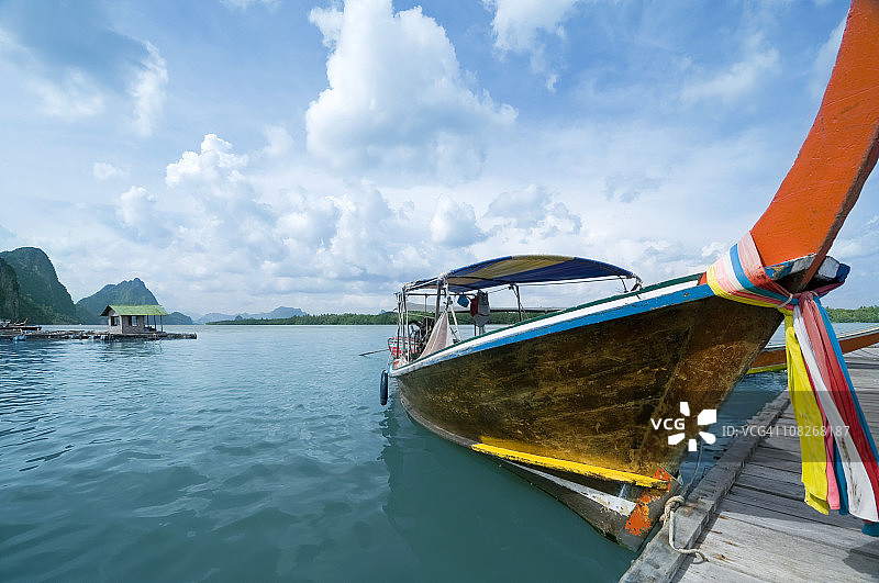 热带岛屿上的长尾船，蓝天碧海，停靠码头图片素材