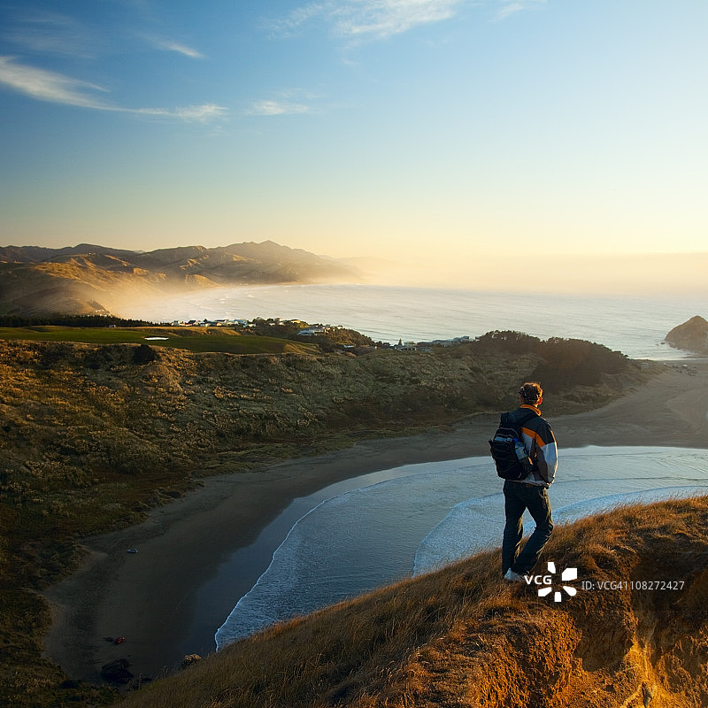 清晨，男子在岩石海岸图片素材