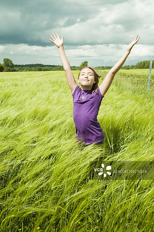 年轻女孩在夏日微风吹拂的麦田里享受大自然图片素材
