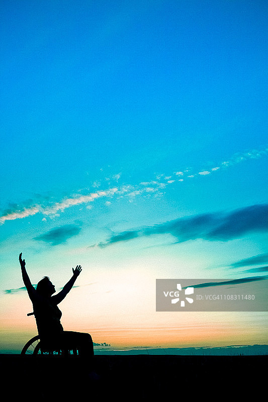 坐在轮椅上伸手向天空的女人图片素材