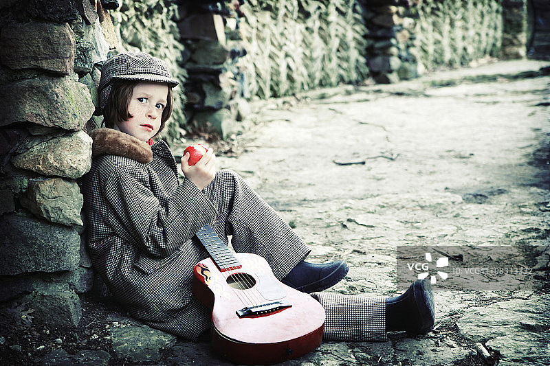 身穿西装、系着领结、抱着吉他、拿着苹果的可爱小音乐家图片素材