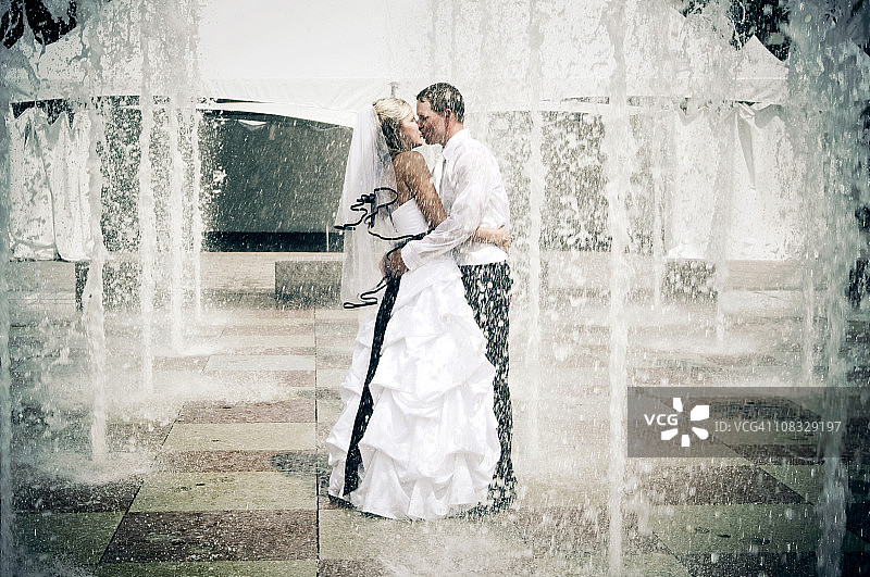 快乐的新婚夫妇：喷泉旁亲吻图片素材