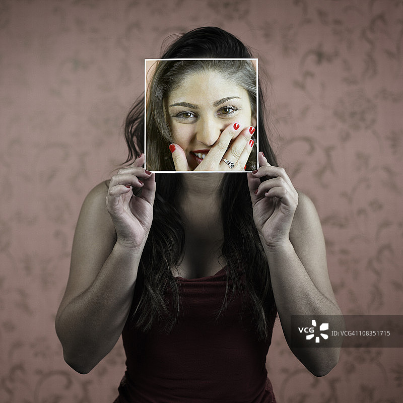 拿着自己脸部照片的女人图片素材