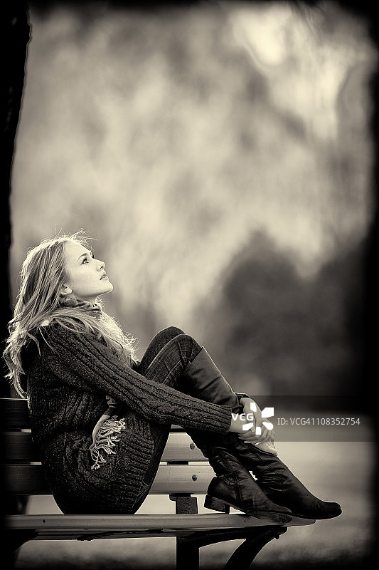 女人坐在长椅上，秋季风格图片素材