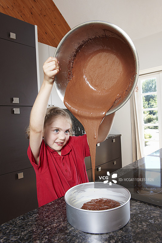 女孩将蛋糕混合物倒入蛋糕模具中图片素材