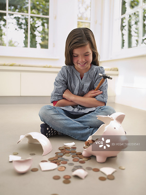 女孩用锤子打破小猪存钱罐图片素材