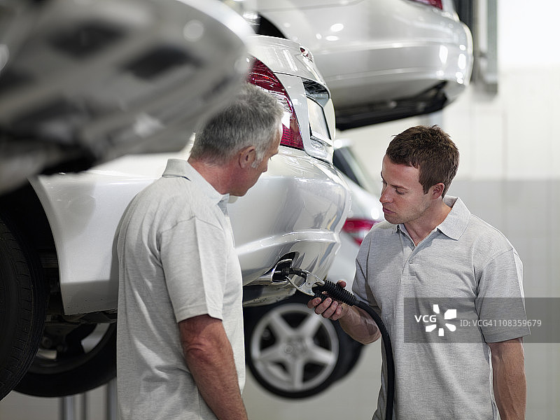 机械师在汽车修理店修理消声器图片素材