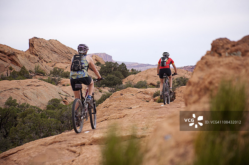 两个女人在犹他州摩押的斯里克岩石路线上骑山地自行车图片素材