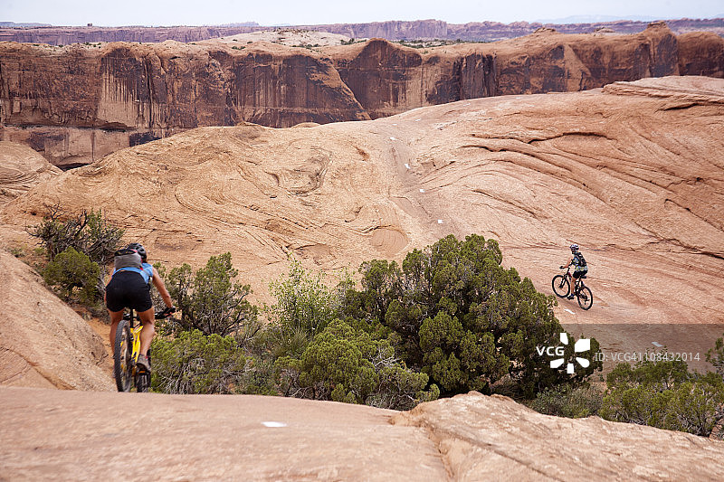 两个女人在犹他州摩押的斯里克岩石路线上骑山地自行车图片素材