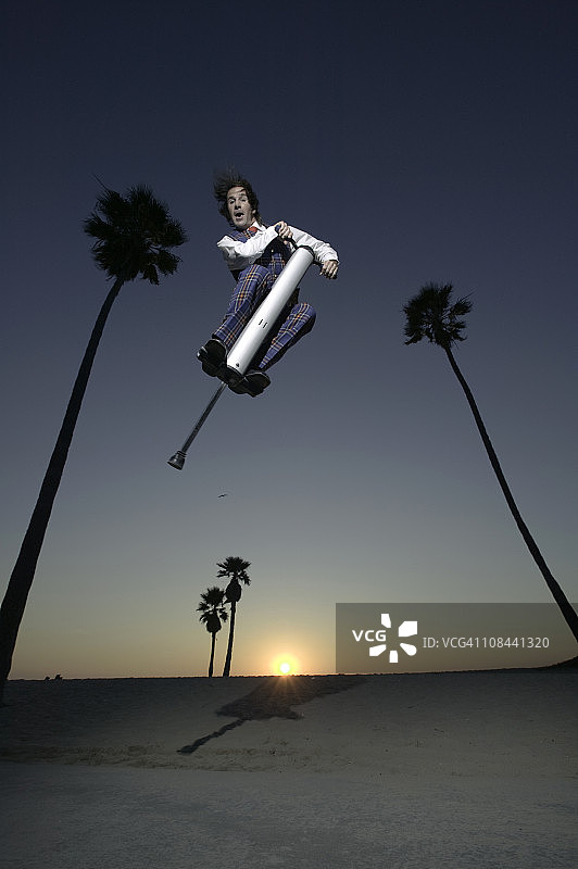 美国加利福尼亚威尼斯海滩日落时分，穿着格子呢的男人在大型弹跳杆上图片素材