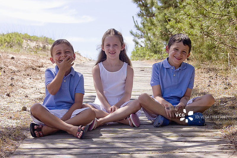 在海滩阴凉处坐着的两兄弟和姐妹图片素材
