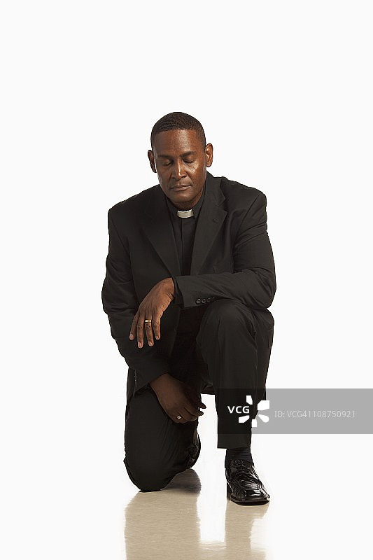 男人戴着牧师领跪地祈祷图片素材