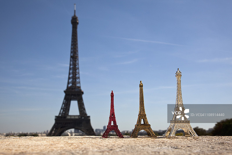 真正的埃菲尔铁塔旁边的三个埃菲尔铁塔复制品纪念品，重点在前景色上图片素材