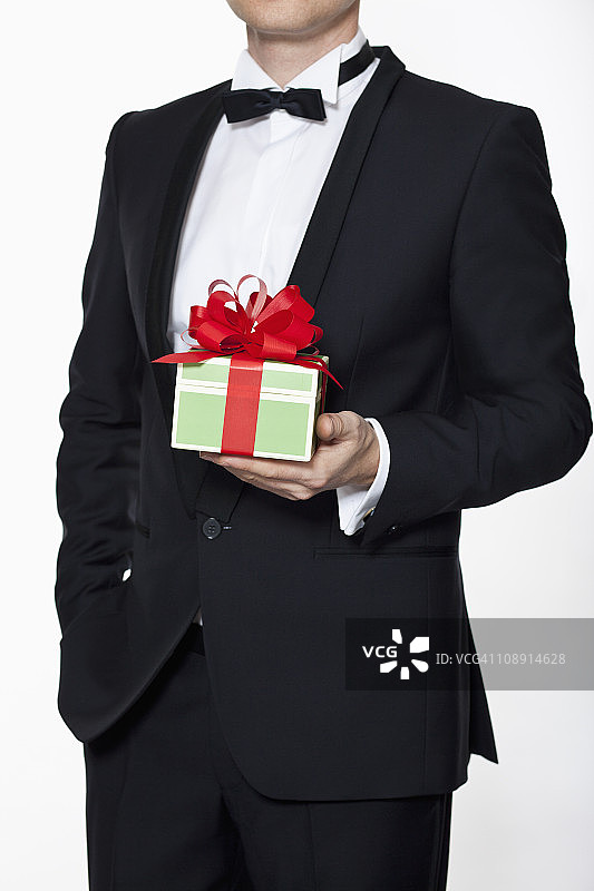 身穿燕尾服的男子拿着生日礼物（局部）图片素材