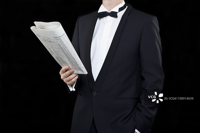 身穿燕尾服，悠闲阅读财经新闻的男人图片素材