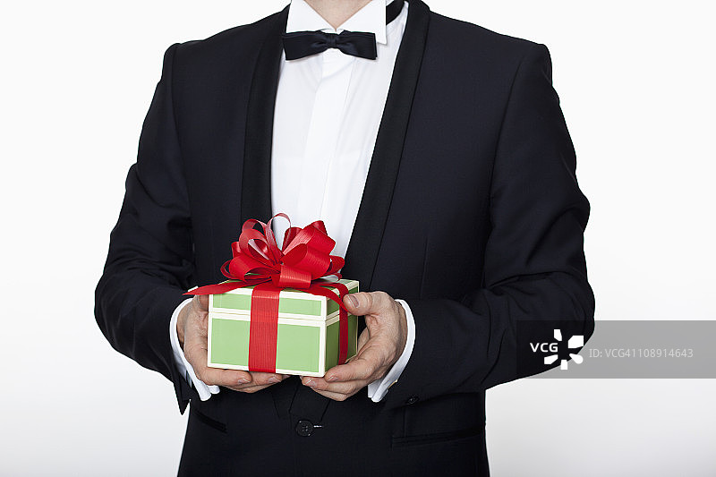 身穿燕尾服的男子拿着生日礼物（局部）图片素材