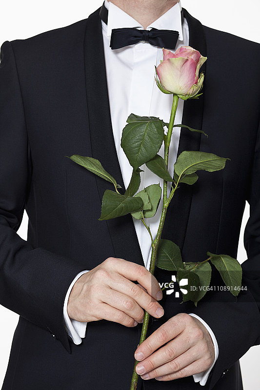 穿燕尾服的男士手持长杆玫瑰图片素材
