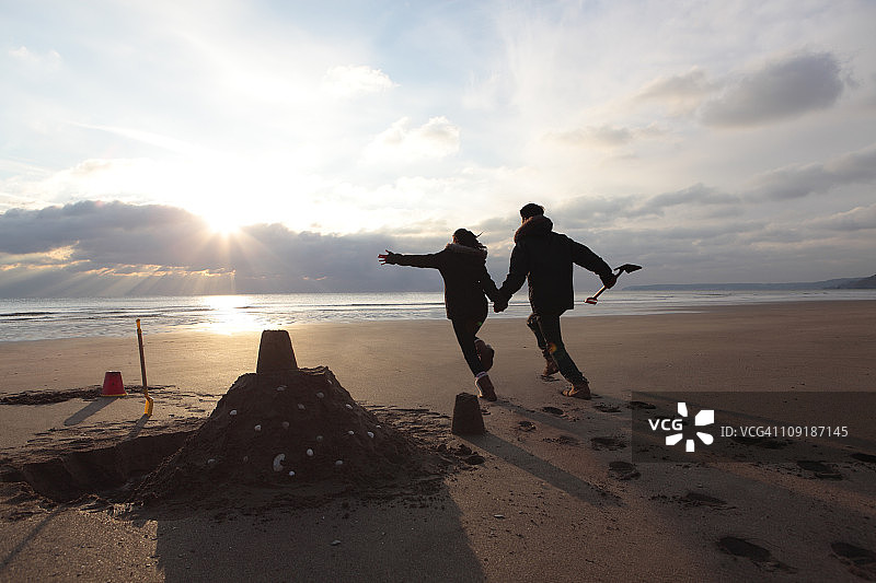 冬天在海滩上玩耍的年轻夫妇图片素材
