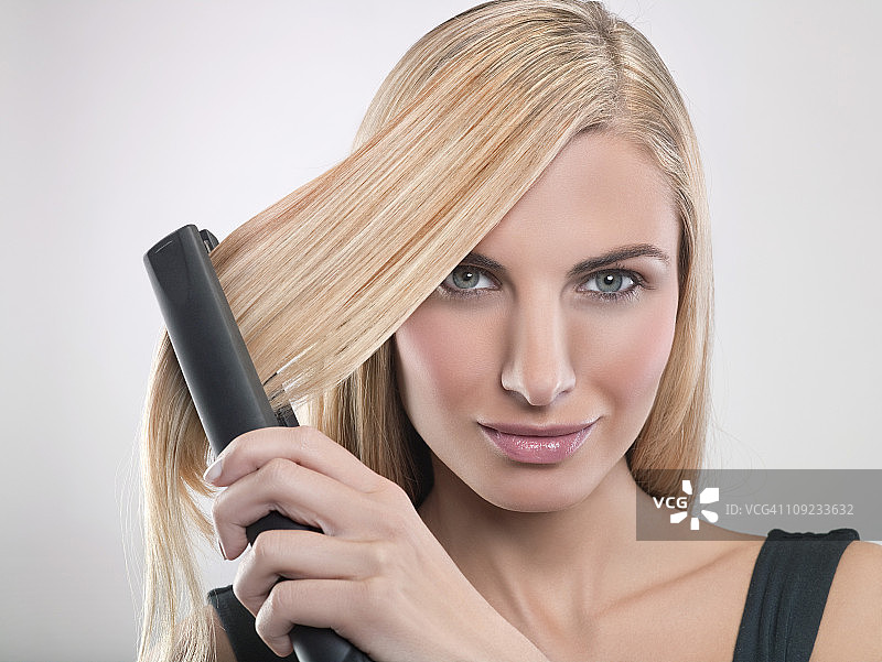 年轻女人使用直发器图片素材