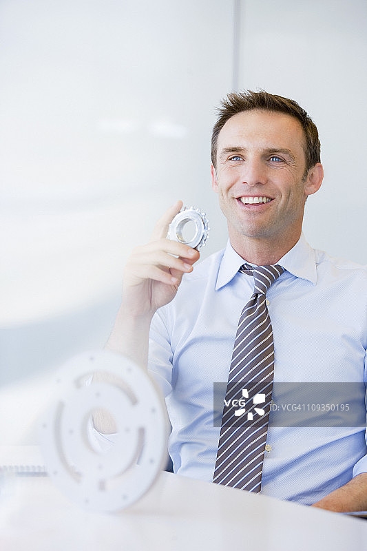 坐在办公桌前拿着齿轮的商人图片素材