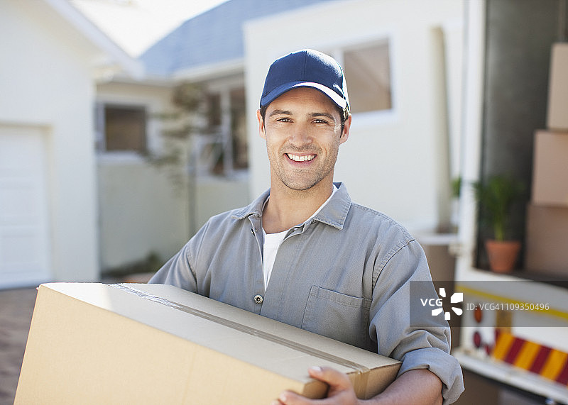 微笑的男人从搬家车上搬运箱子图片素材