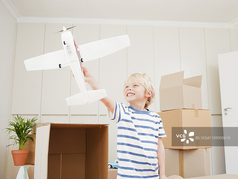 男孩在新房子里玩飞机模型图片素材