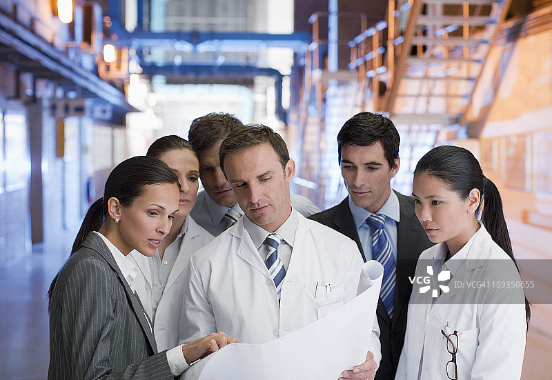 商人和科学家在工厂里看蓝图图片素材