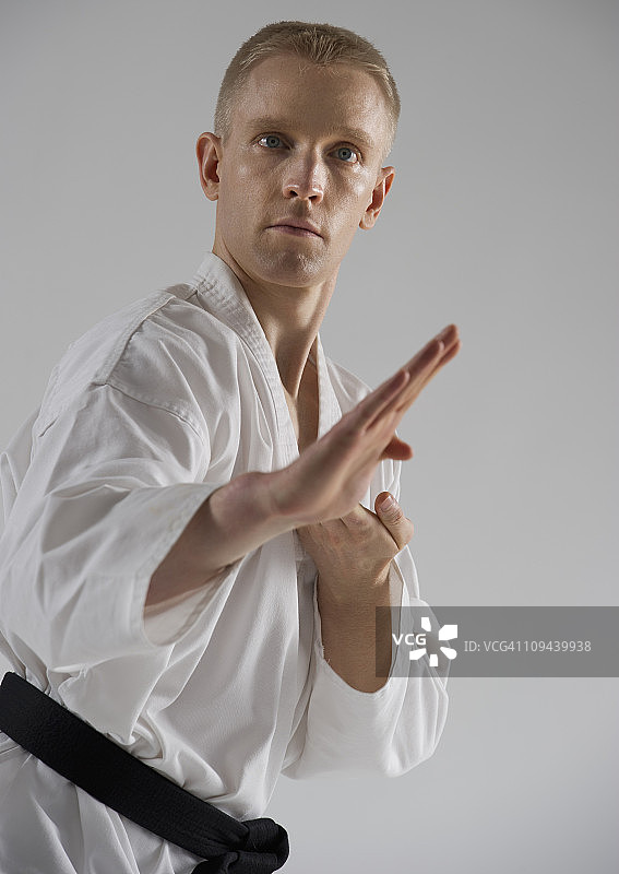 年轻男人在白色背景上摆出空手道姿势图片素材