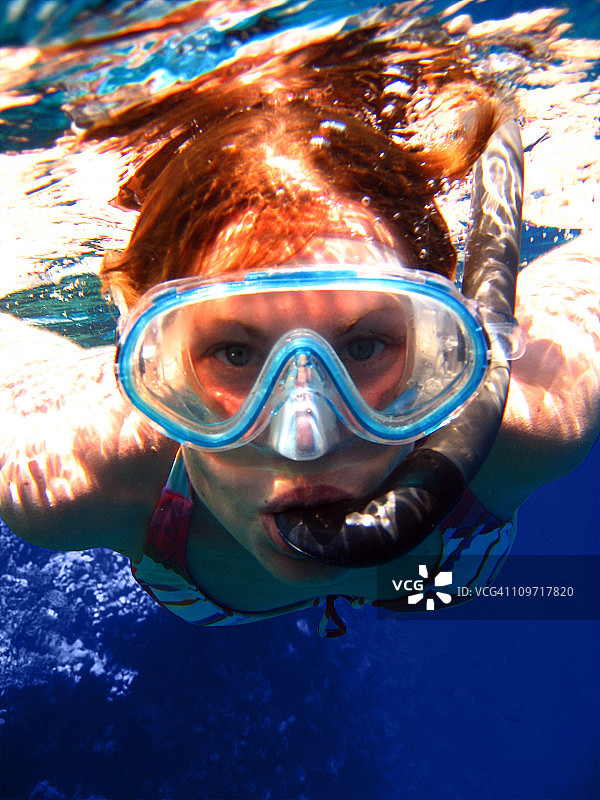 戴着潜水面罩在水下游泳的年轻女人图片素材