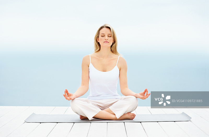 在码头上以莲花坐姿坐着的年轻女孩图片素材