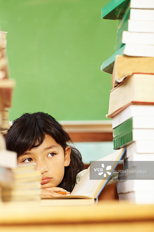 坐在书堆中的亚洲小女孩图片素材