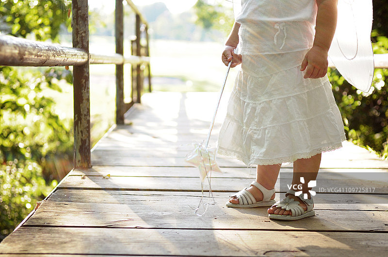 在桥上穿着仙女翅膀、拿着仙女棒的小女孩图片素材