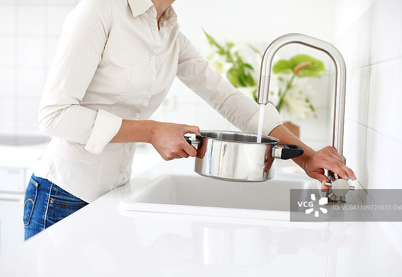 在水槽边拿着平底锅的女人图片素材