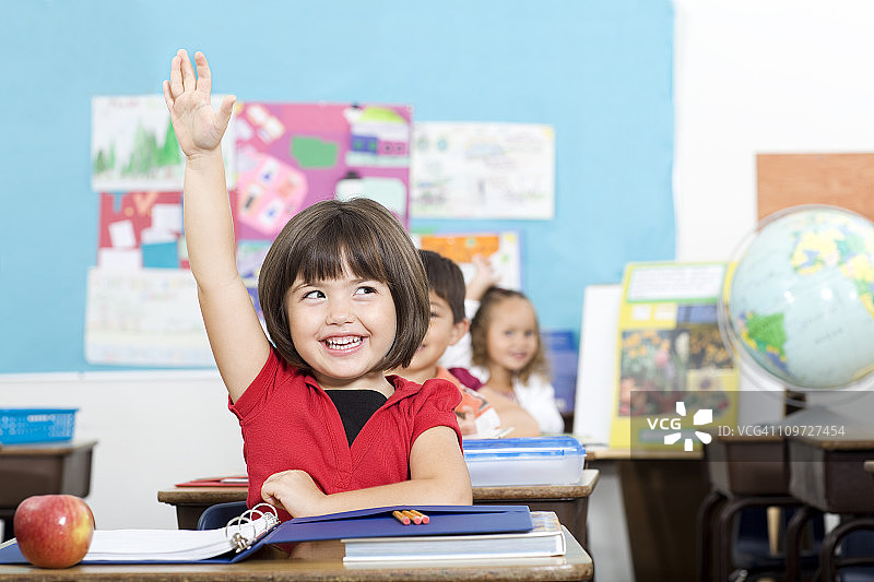 在小学教室里举手，兴奋的可爱小学生图片素材