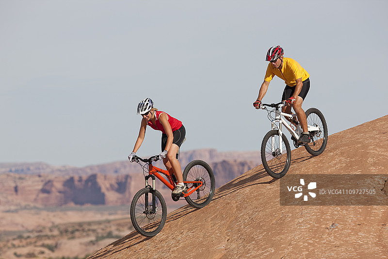 犹他州莫阿布的两位骑山地自行车的自行车手下坡图片素材