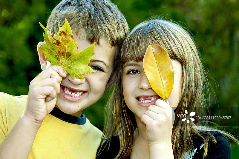 两个孩子用树叶遮住眼睛图片素材