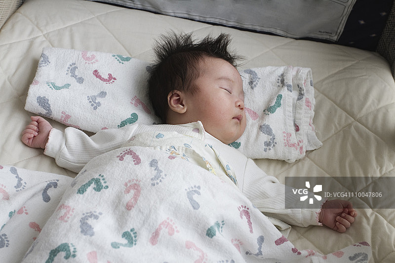 在婴儿床中睡觉的中国新生女婴图片素材
