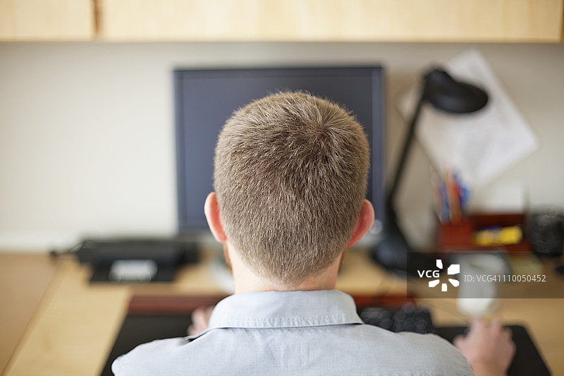 男人在电脑前工作的背面视角图片素材