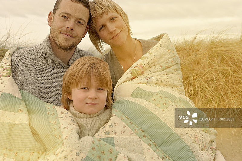 一家人在海滩上依偎在被子里图片素材