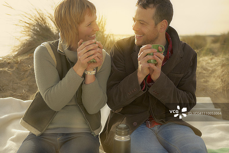 情侣在海滩上用咖啡壶喝咖啡图片素材