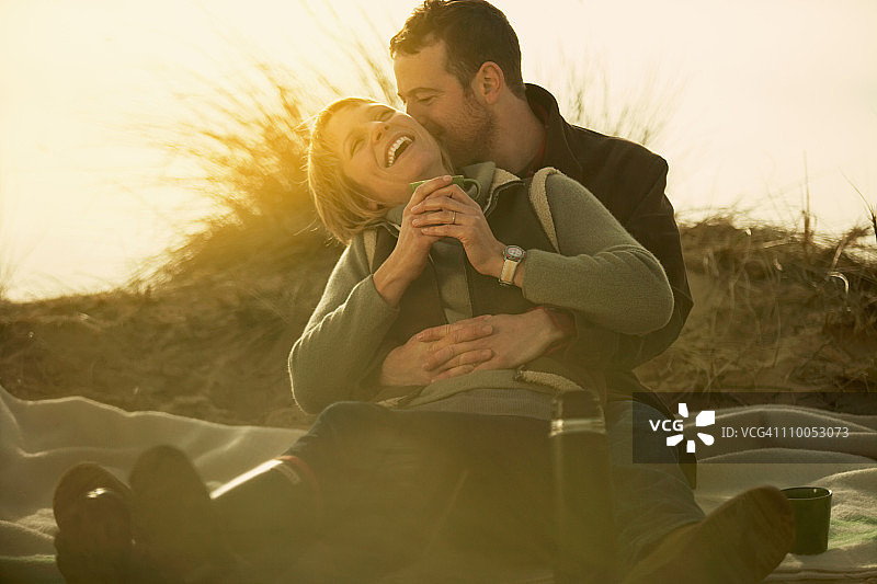 情侣在沙滩上拥抱，喝咖啡图片素材