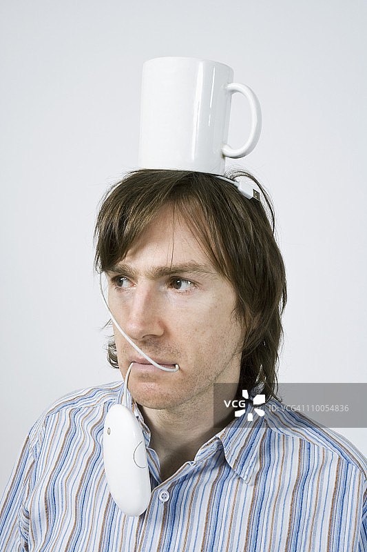 男人平衡咖啡杯和鼠标图片素材