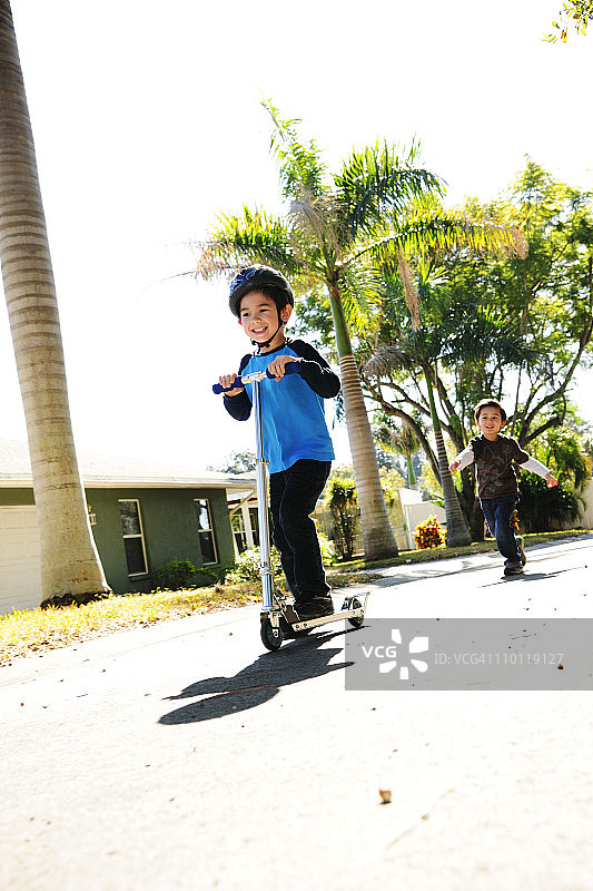 兄弟俩在户外骑滑板车图片素材